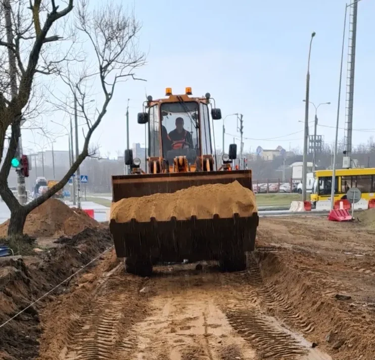 Фронтальный погрузчик из нашего автопарка спецтехники в Минске везёт песок в ковше на объекте благоустройства тротуара по ул. Свислочской